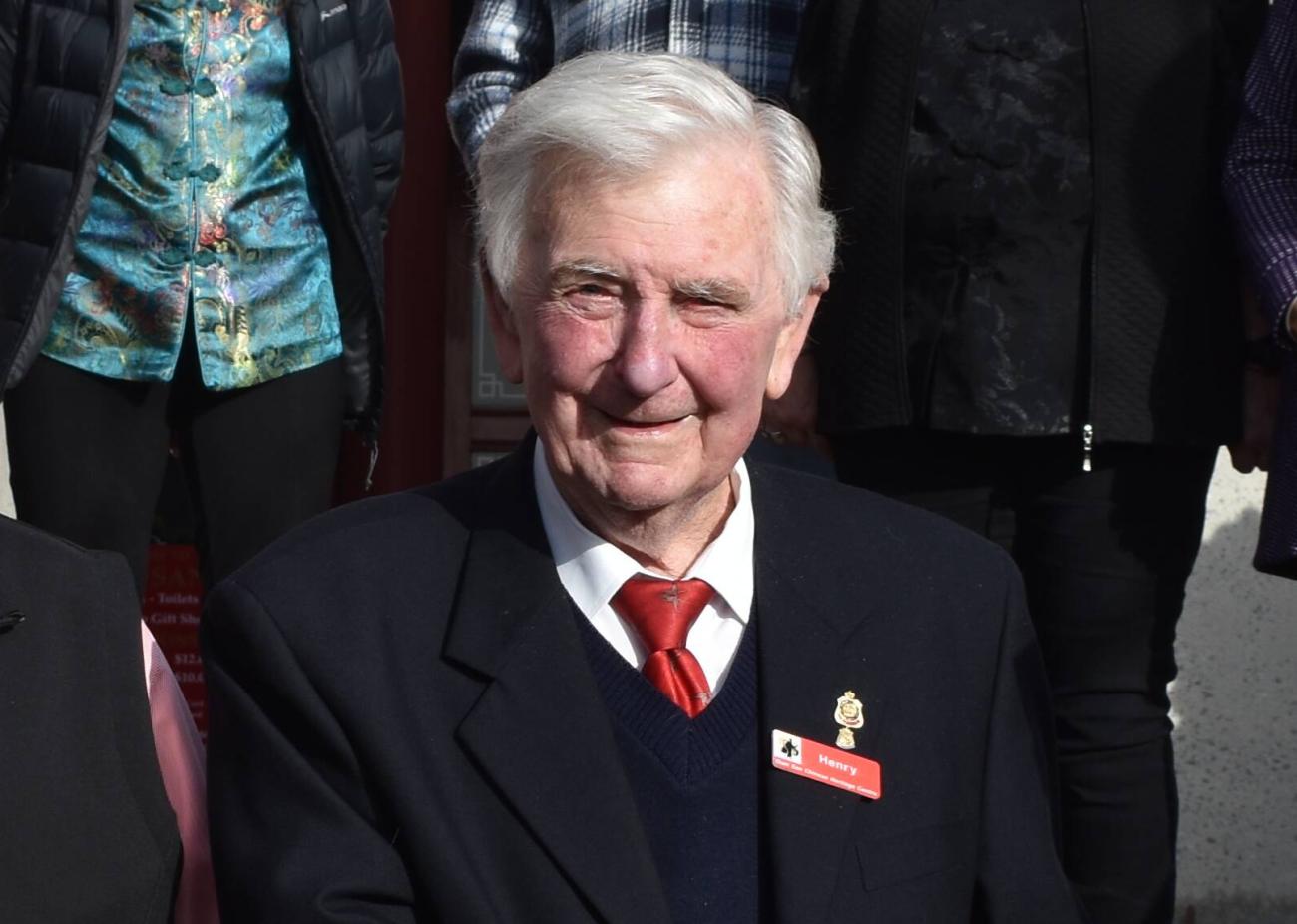 Man with white hair and a navy suit at a Council event, smiling at camera