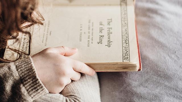 Child sitting cross-legged reading a novel