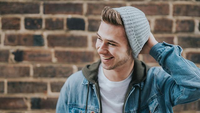 Teenaged boy in denim jacket and beanie laughing