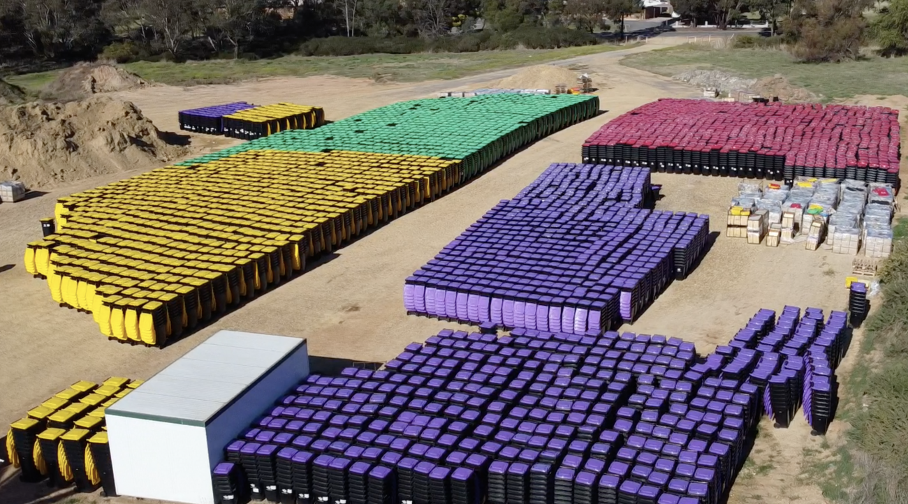 Aerial shot of many hundreds of plastic bins, grouped together in their colours of purple, yellow, green and red