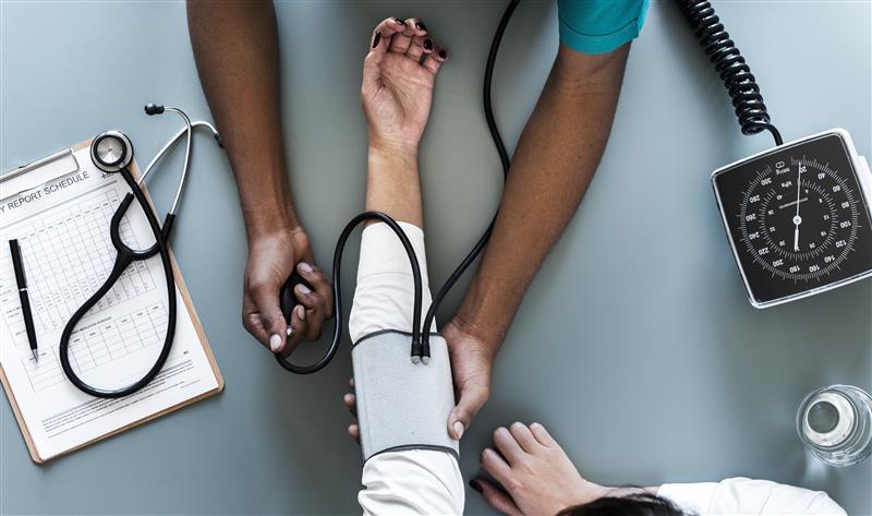 Birds-eye view of a doctor taking a woman's blood pressure