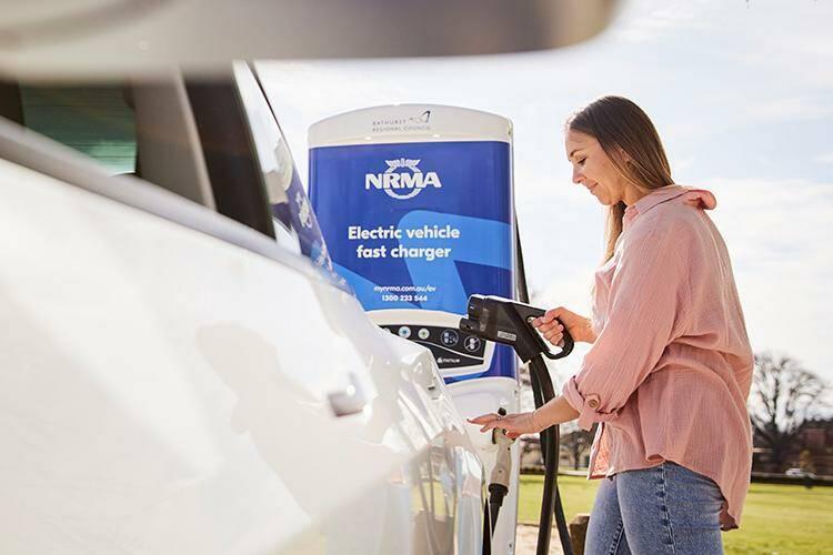 Woman charging her electric vehicle with a far car charger