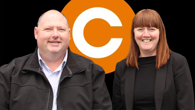 Bald man and woman with red hair smiling, with a large orange C logo behind them