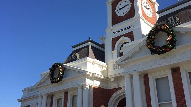 Large municipal building with two Christmas wreaths hung on its pillars