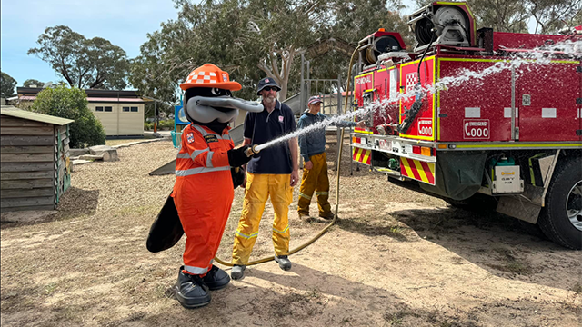 A large platypus mascot holding a firehose with the CFA