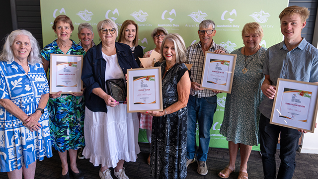 Group of people smiling and holding framed awards