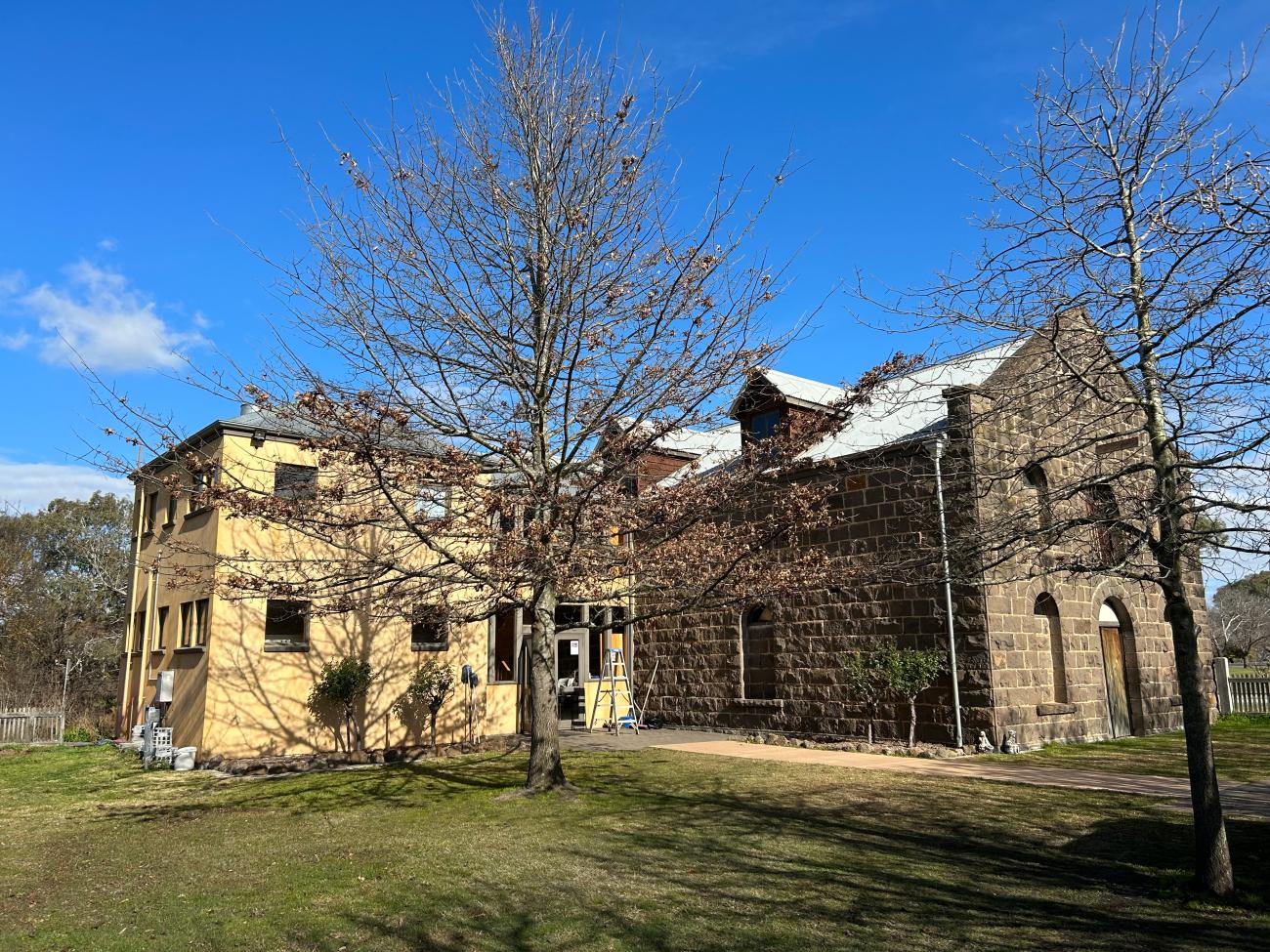 A historic stone building with a large tree in the foreground.