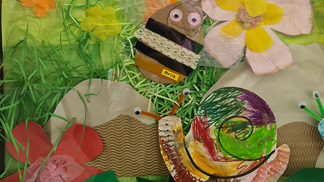 Close-up of children's craft artworks, including bees, snails and other insects in a garden scene