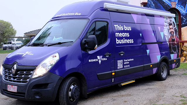 A minibus with a purple wrap and the slogan 'This Bus Means Business'