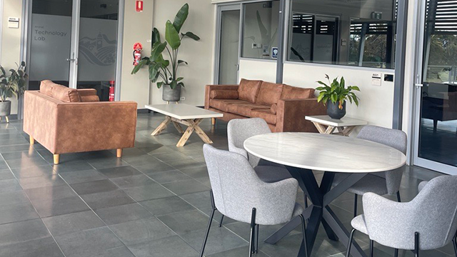 The inside of a modern building foyer with plants and sitting areas