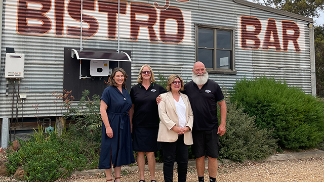 Four people smiling and standing outside a rural bistro